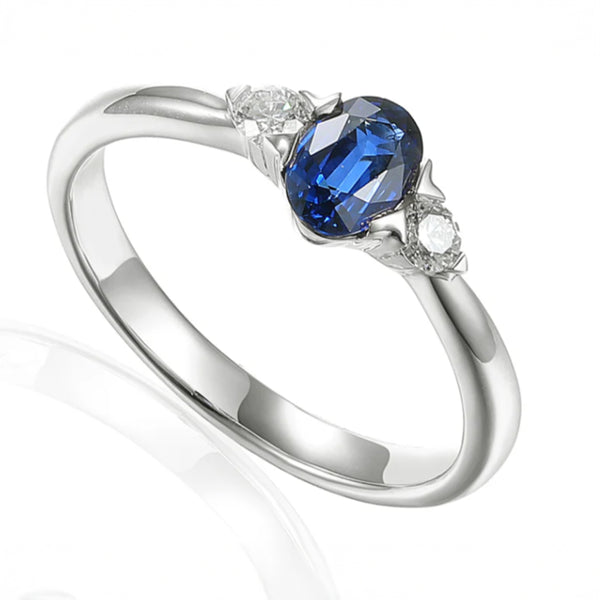 Platinum 0.51ct Oval Cut Blue Sapphire And 0.13ct Round Brilliant Cut Diamond Three Stone Ring